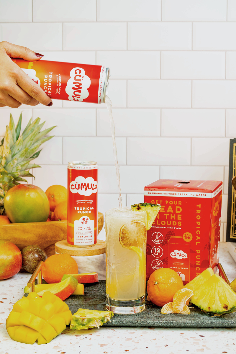 Cumulo Tropical Punch being poured into a glass with sliced pineapple