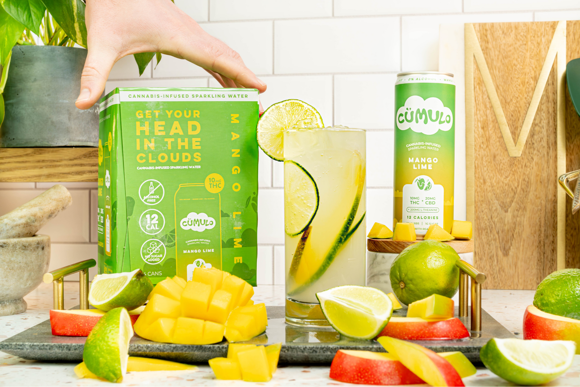 A case of Cumulo Mango Lime hemp-derived seltzer with limes and mangos on a countertop